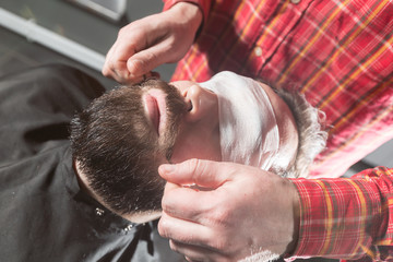 Naklejka premium Barber is making the beard shape. Beard cutting, face care. Work in barber shop salon.