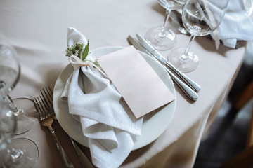 Wedding table setting. White plates, glasses, cutlery and napkins lie on the dinner round table...