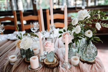 Wedding decor elements. Flowers, crystal vases, candles and greens on the holiday table