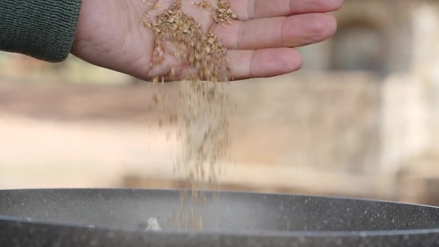 Adding crushed coriander to a steaming pot of food while cooking