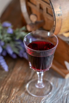 A glass of red wine and a bouquet of lavender flowers next to a wine wooden barrel. Art photography. Closeup. Soft focus.Toned image doesn’t in focus.