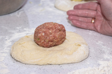 raw meatball on a round piece of dough will be used as a filling in a pie. Baking concept