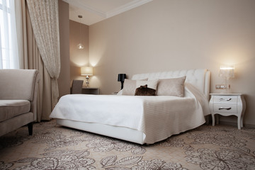 Luxury design interior of hotel room in soft brown and beige color tone. Peace and quiet. Sweet home. King size bed in the middle of the room.