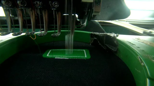 Running Embroidery machine with embroidery logo at T-shirt in Garment Textile Manufacture Industry