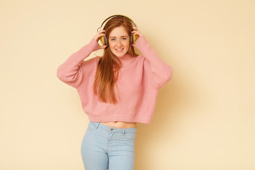 Beauty shoot of young fresh, full of energy girl with ginger hair listening to music.