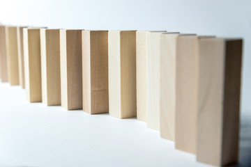 A long curved line of wooden cubes, as a symbol of a queue, competition for a position or team, on a uneven white background. Horizontal frame