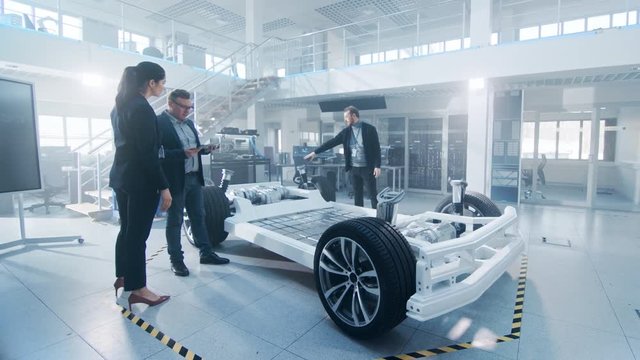 Automotive Design Engineer Shows the Electric Car Chassis Prototype to the Management Board Representatives. Concept Includes Wheels, Hybrid Engine and Battery.