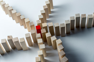Many curved lines of wooden cubes are combined in the center into one red, as a symbol of queues, a variety of tasks and a leader, on an uneven white background. Horizontal frame