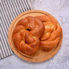 Delicious pretzels. Sweet bun on a wooden board. Striped serviette. Top view.