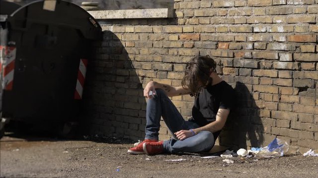 young drug addict man sitting in the street.degradation,drug addiction,lonelines