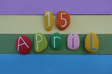 15 April, calendar date with colored stones over a multi colored wooden board