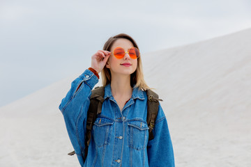 Travel girl with backpack in a sunglasses on a sand beach