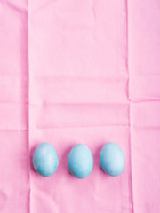Blue pastel easter eggs on pink table cloth. Festive flat lay