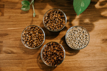 Glass Container Cups of Coffee Espresso Beans Roasted and Raw Green Beans on Wooden Product Display Table