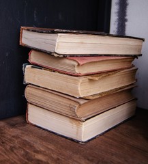 Four books stacked vertical on wood shelf