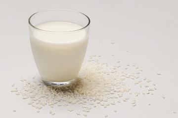 Rice milk and white rice. Organic vegan non-dairy plant-based milk in a glass.