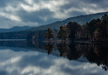 Mirrored reflection on a mountain lake in Northern Arkansas. The adverse weather gives an ominous...