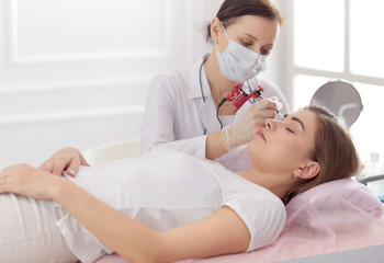 A young girl having red lips permanent makeup, micropigmentation