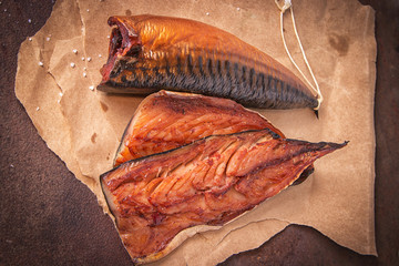 Smoked mackerel fillets on craft paper on a rustic rusty metal table. Top view