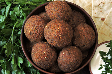 Fresh homemade falafel in a bowl with sauce, parsley and pita. Middle Eastern cuisine.