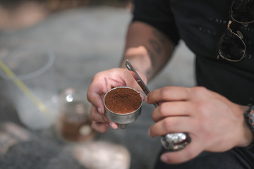 A person is putting coffee powder with into a silver coffee machine