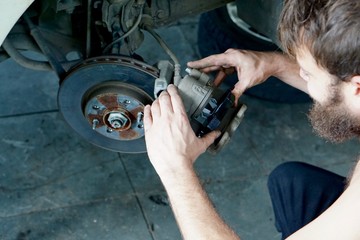 A car mechanic installing new brake pads on a car wheel hub