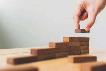 Hand arranging wood block stacking as step stair. Ladder career path concept for business growth...