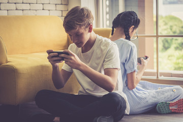 Boy and Girl lean back together and playing game in mobile phone