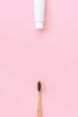 Natural eco-friendly bamboo brush with black bristles and tube of toothpaste. Set for washing on paper pink background. Copy space for text or your design Top view Flat lay.