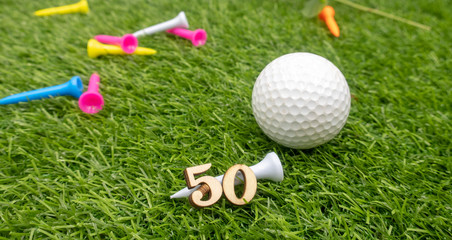 Naklejka premium 50th birthday to golfer with golf ball and tee on green grass