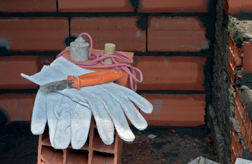 Protective gloves and masonry tools on pile of bricks