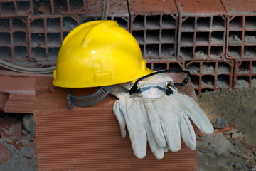 Gloves, helmet and mason's goggles on pile of bricks
