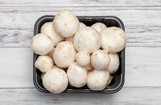 Heap of champinion mushrooms in a basket on a wooden background