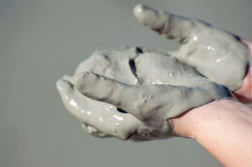 Hands covered with grey mud, held open and face up - close up