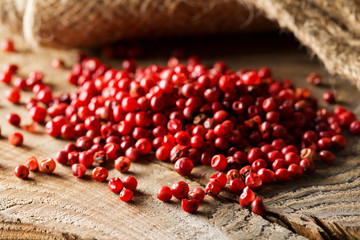 Pink or rose brazilian red peppercorns (schinus terebinthifolius) on rustic wooden table background
