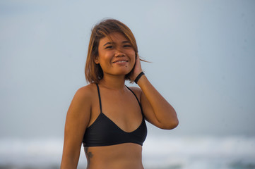 young exotic and charming Asian girl in bikini smiling relaxed and carefree enjoying holidays at tropical beach happy and cheerful having fun at the sea