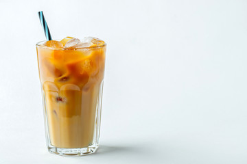 Ice coffee in a tall glass with cream poured over and coffee beans. Cold summer drink on a light background. With copy space