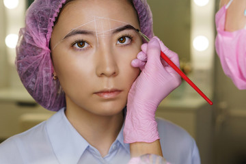 Microbleeding and eyebrow architecture. Cosmetologist applies coloring pigment to eyebrows of girl,...