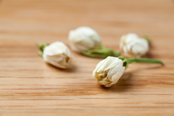 Dried jasmine flowers tea on wooden table.
