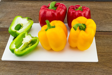 still – life concept colorful sweet bell pepper (capsicum)   in white block   on wooden background