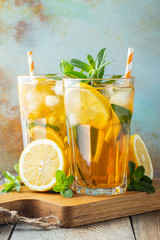Traditional iced tea with lemon and ice in tall glasses on a wooden rustic table. With copy space