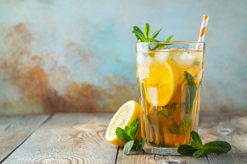 Traditional iced tea with lemon and ice in tall glass on a wooden rustic table. With copy space