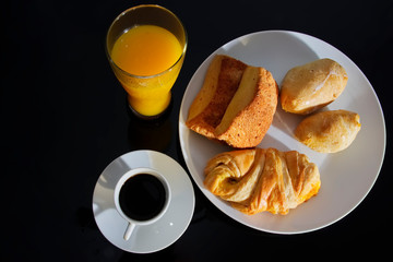 Breakfast. Coffee white cup, plate with bread croissants on dark table