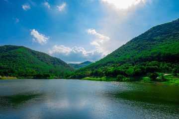 street view with green mountain on blue sky background in the province of Thailand. decoration image contain certain grain noise and soft focus.