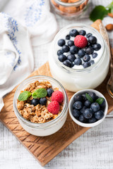 Granola, Blueberries, Raspberries And Yogurt In Jar On Wooden Board. Top view