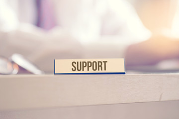 Ein Mann im Büro und Schild mit dem Aufdruck Support