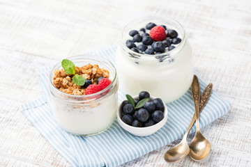 Greek yogurt with berries and granola cereals in jar on blue checkered napkin. Food for dieting, weight loss, healthy lifestyle, healthy breakfast or snack