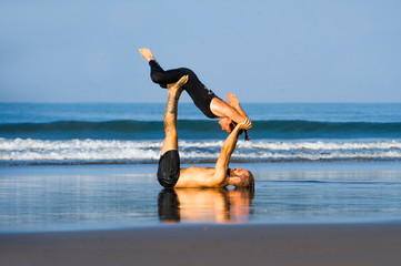 young attractive and beautiful acrobat couple practicing acroyoga exercise concentrated keeping...