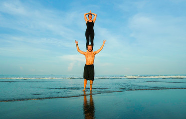 young attractive and beautiful acrobat couple practicing acroyoga exercise concentrated keeping...