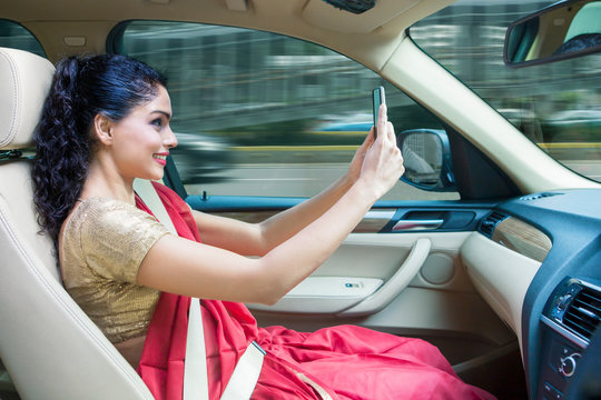 Young Indian woman taking a photo in the car